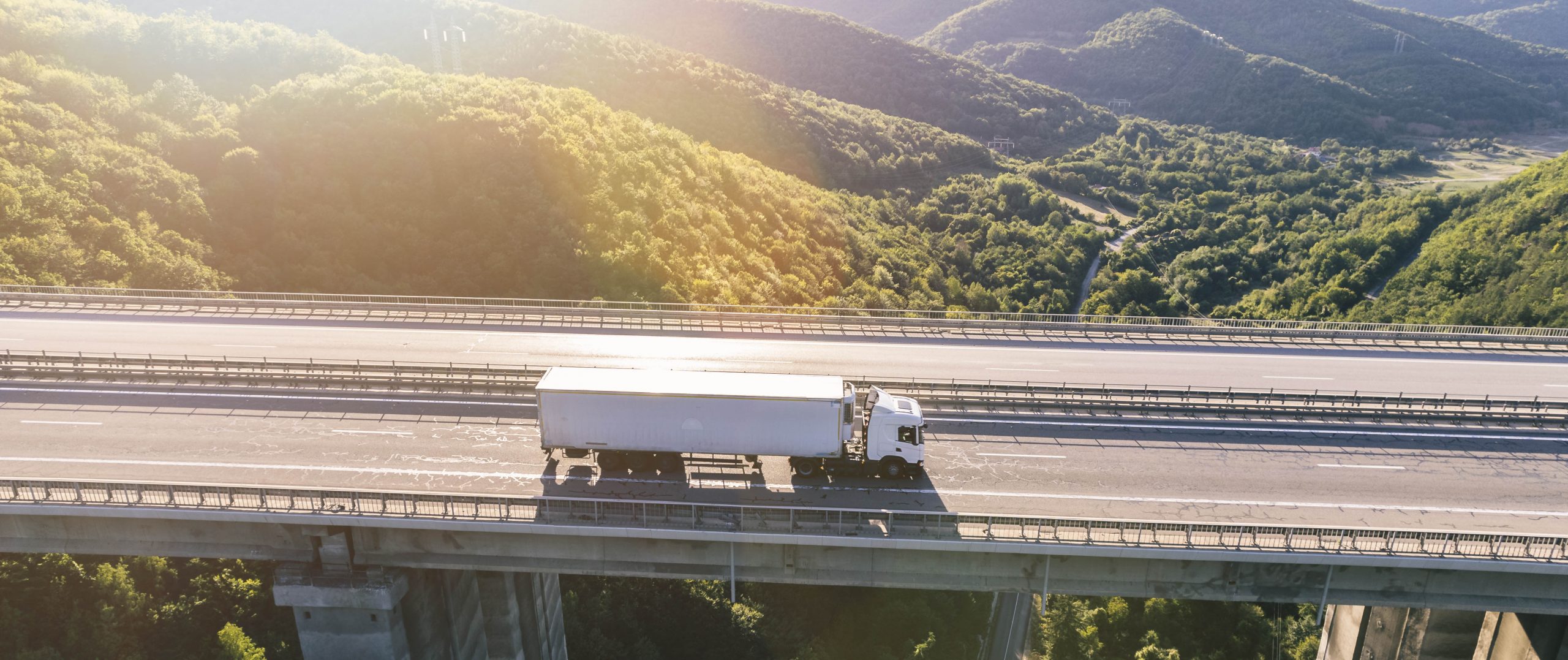 trucks on highway in mountain at sunset aerial view